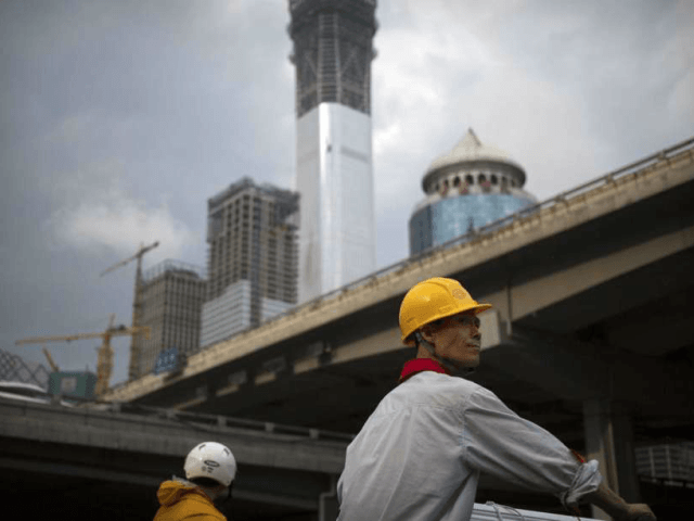 FILE - In this Aug. 16, 2017, file photo, a construction worker waits to cross an intersec