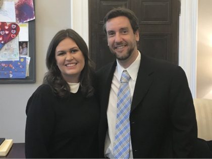 Clay Travis and Sarah Huckabee Sanders pose together for a picture in the White House on December 5, 2017.