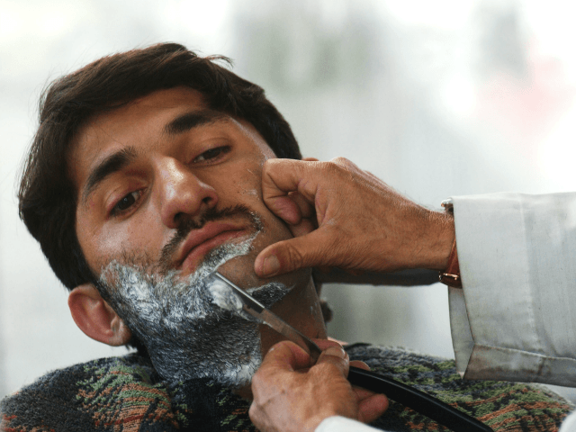 An Afgan man has his beard shaved at the Fazal Mohammad Barber Shop March 4, 2003 in Kabul