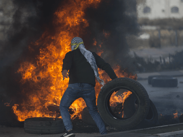 A Palestinian protester burns tires during clashes with Israeli troops following protests