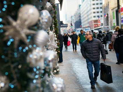 NEW YORK, NY - DECEMBER 18: A man carrying a shopping bag walks past holiday decorations a
