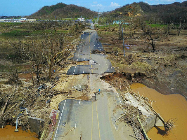 A man rides his bicycle through a damaged road in Toa Alta, west of San Juan, Puerto Rico,