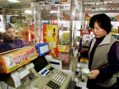 Store owner April Kim makes a sale to an African-American customer from inside a protectiv