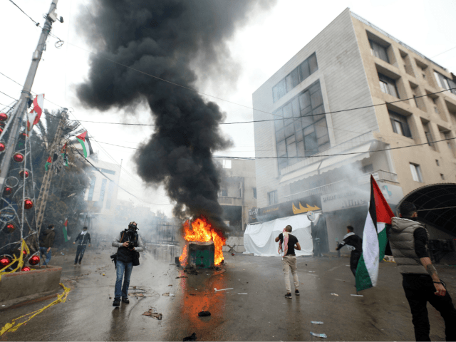 Lebanese security forces fire tear gas to disperse protestors as a fire burns in a dumpste