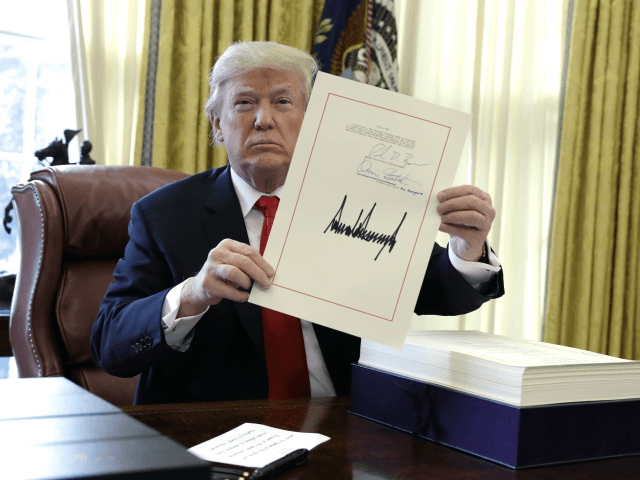 President Donald Trump displays the $1.5 trillion tax overhaul package he had just signed, Friday, Dec. 22, 2017, in the Oval Office of the White House in Washington. Trump touted the size of the tax cut, declaring to reporters in the Oval Office before he signed it Friday that "the …
