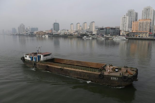 A North Korean ship passes in front of the Chinese border city of Dandong (at rear), in Ch