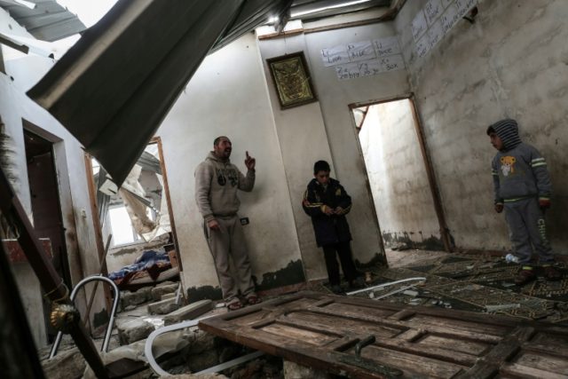 A Palestinian man and children check their house that was damaged in an Israeli airstrike