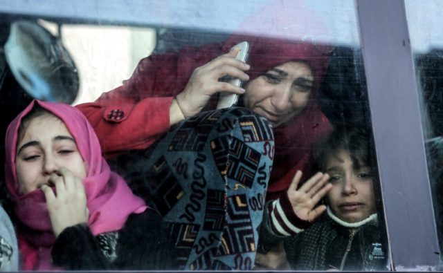 A Gazan woman and child bid farewell through the window of a bus as they head for the Rafa