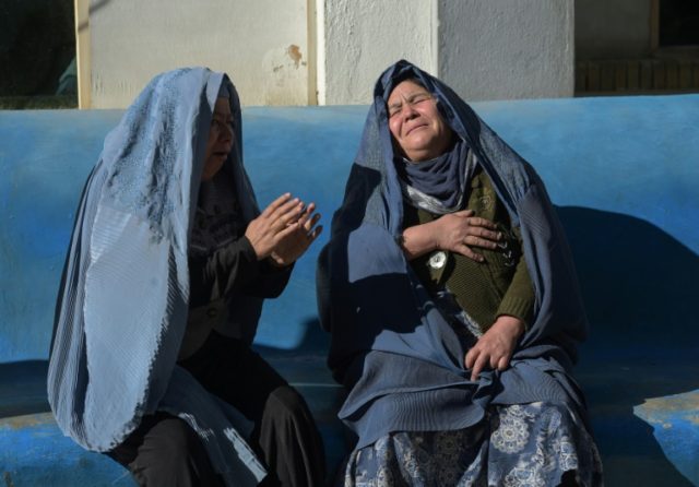 Two Afghan women weep for their relatives at a hospital following an attack on a Shiite cu