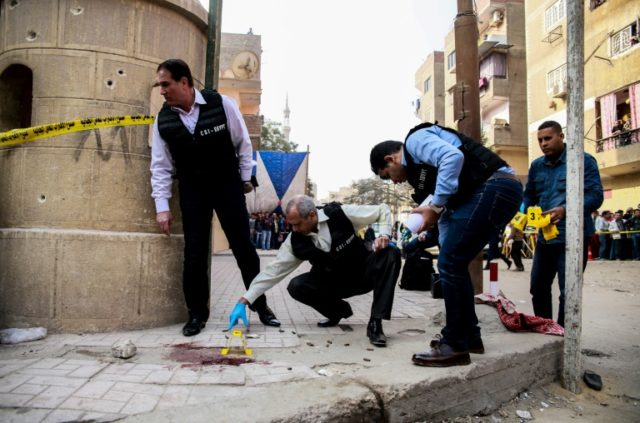 Egyptian security members and forensic police inspect the site of a shooting outside a chu