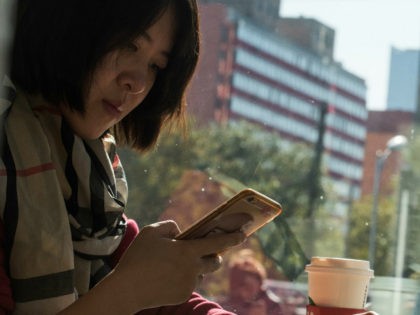 A woman uses her smartphone in Beijing on November 11, 2017. China's smartphone masses splurged billions of dollars in an e-commerce bonanza on November 11 as consumers rushed to snap up bargains on 'Double 11', billed as the world's biggest one-day online shopping festival. / AFP PHOTO / FRED DUFOUR …