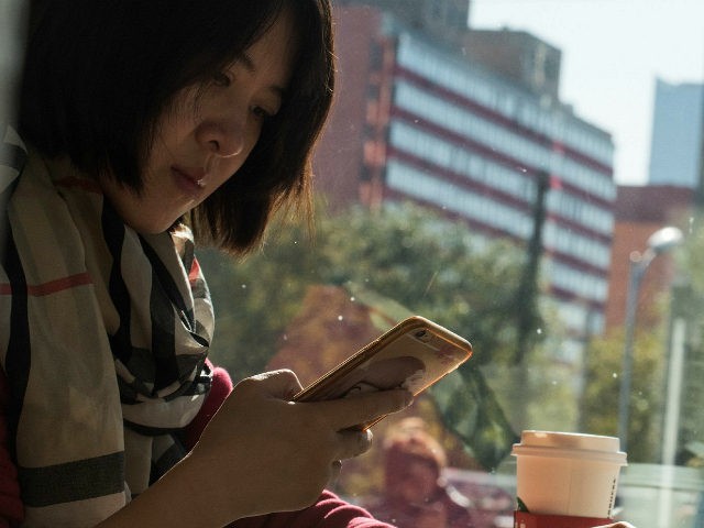 A woman uses her smartphone in Beijing on November 11, 2017. China's smartphone masses spl