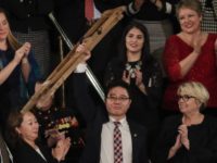 Ji Seong-ho holds up his crutches after his introduction by President Trump during the Sta