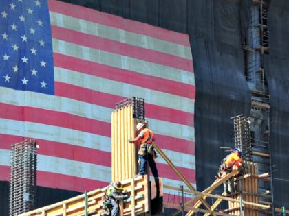 Construction workers work the construction of a new building partly covered with a large U