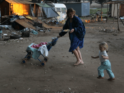 KRUGERSDORP, SOUTH AFRICA - JUNE 07: Chantell Lubbe carries a plate full of free food while walking with her children through a White South African squatter camp on June 7, 2010 in Krugersdorp, South Africa. The local municipality tried to evict the squatters from the land last year to make …
