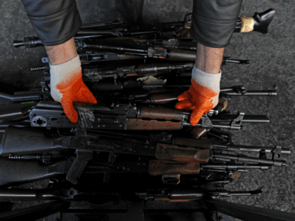 A Kosovar employee shows seized weapons before destroying them at a metal foundry near the