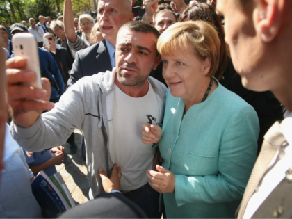 BERLIN, GERMANY - SEPTEMBER 10: German Chancellor Angela Merkel pauses for a selfie with a migrant after she visited the AWO Refugium Askanierring shelter for migrants on September 10, 2015 in Berlin, Germany. Merkel visited several facilities for migrants today, including an application center for asylum-seekers, a school with welcome …