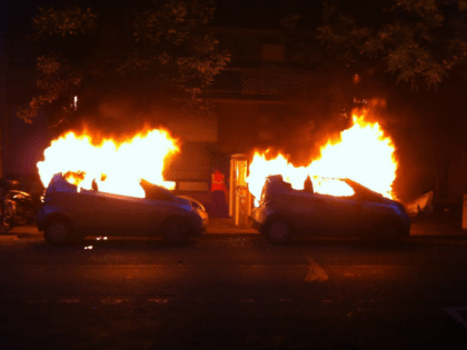 TOPSHOT - A photo taken on June 14, 2016 shows two Autolibs (the French electric car pick-up service) on fire in a street of Paris after been burnt by a group of hooded people. / AFP / Samantha DUBOIS (Photo credit should read SAMANTHA DUBOIS/AFP/Getty Images)