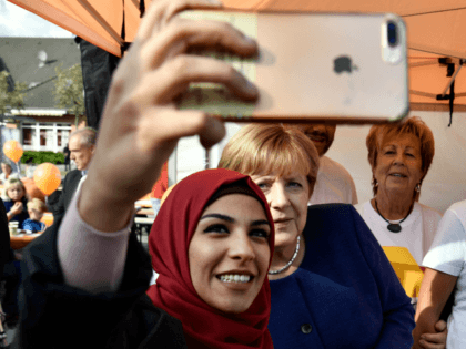 A syrian refugee (L) poses for a selfie photo with German Chancellor Angela Merkel (C) as she continued on the election campaign trail in Stralsund on September 16, 2017, a week before Germans head to the polls. / AFP PHOTO / John MACDOUGALL / ALTERNATIVE CROP (Photo credit should read …