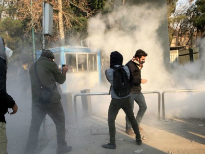 Iranian students run for cover from tear gas at the University of Tehran during a demonstr