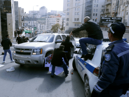 Palestinian activists throw tomatoes at a vehicle transporting members of an American econ