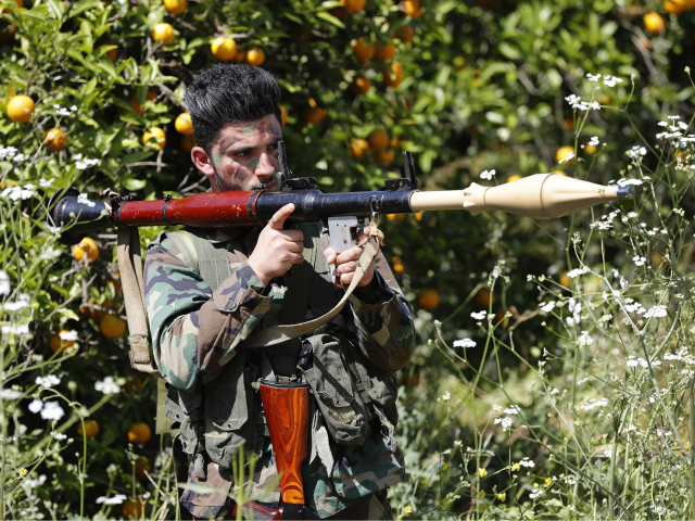 A Hezbollah fighter holds an RPG as he takes his position between orange trees, at the coa