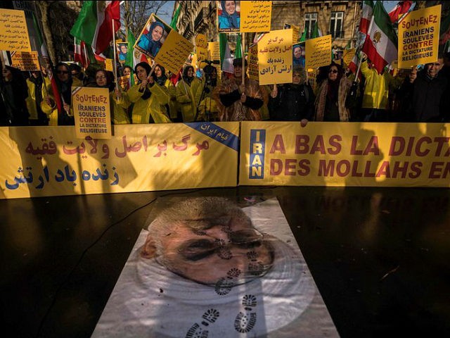 TOPSHOT - Protesters hold placards reading 'Support Iranians risen up against the religious dictatorship' as they stand behind a portrait of Iranian President Hassan Rouhani with shoe marks over it during a demonstration in support of the Iranian people amid a wave of protests spreading throughout Iran, on January 3, …