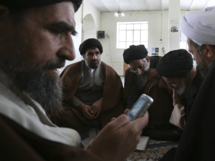 Shiite clerics talk, as one of them check his cell phone, at the Sadr seminary in the city