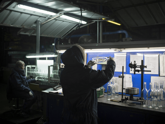 In this Wednesday, Jan. 27, 2016 photo, an employee checks the quality of glass bottles on