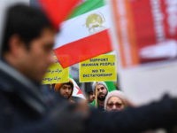 Protesters hold a placard under a flag of the National Council of Resistance of Iran (NCRI) during a demonstration in support of the Iranian people amid a wave of protests spreading throughout Iran, on January 3, 2018, in Brussels. Violent demonstrations have rocked Iran since December 28, 2017, leaving at …