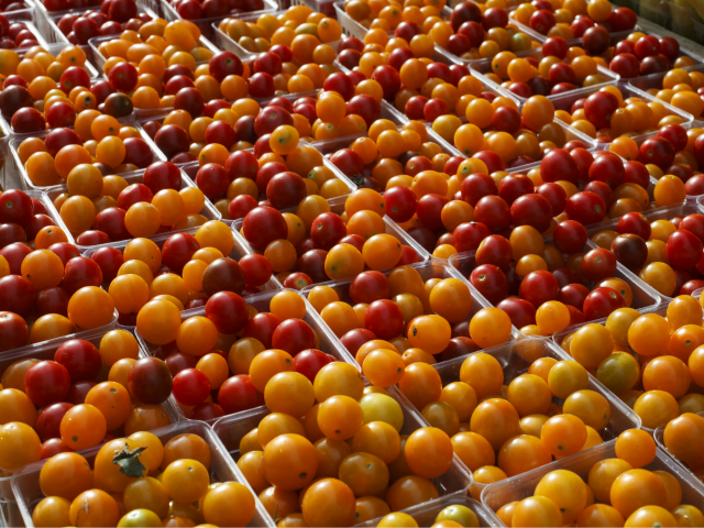 Cherry tomatoes are displayed for sale with summer fruits and vegetables at a farmers mark