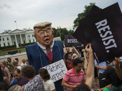 TOPSHOT - Protesters hold up signs near a US President Donald Trump puppet during a rally