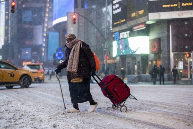 An elderly woman makes her way through New York's Times Square as snow pelts the Big Apple