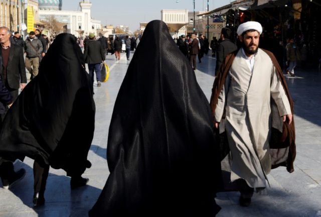 Tourists and clerics walk near the Massoumeh shrine in the holy city of Qom, south of Tehr