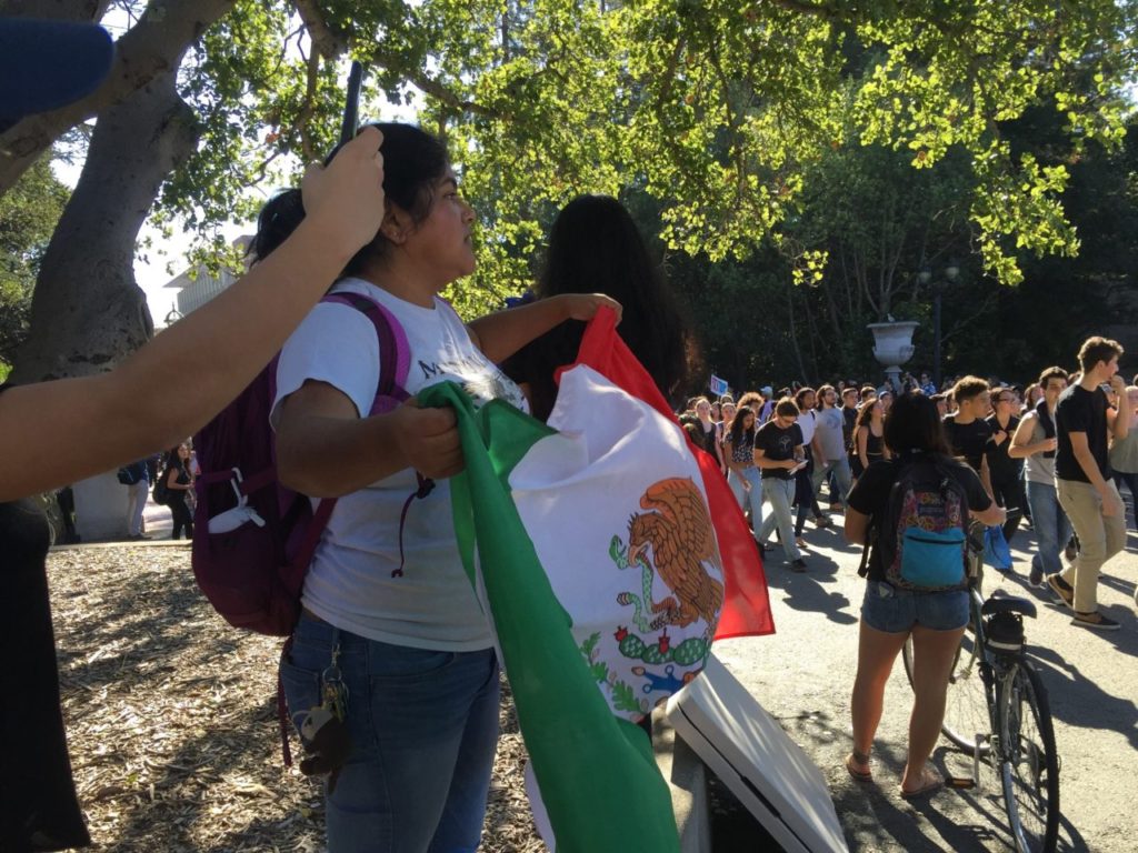 A woman holds a Mexican flag on the campus of UC Berkeley