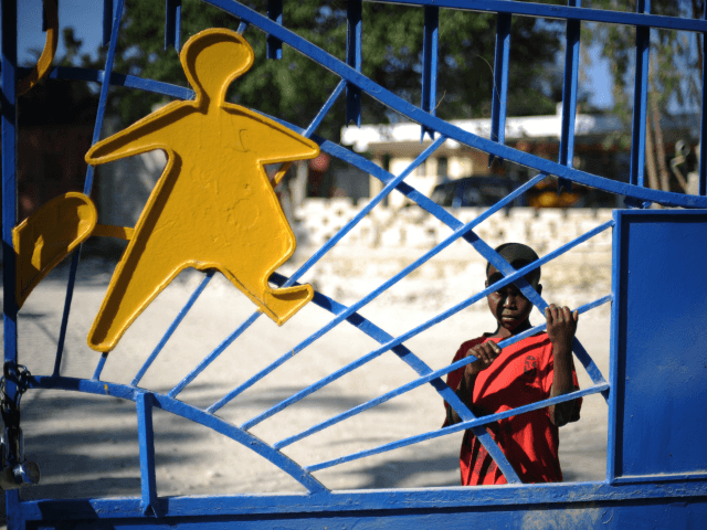 A child waits at the gates of the SOS Children's Village in Croix des Bouquets, outside of Port-au-Prince on February 1, 2010. Ten members of a US Christian group charged with child-trafficking in Haiti could be tried in the United States and will possibly go before a judge later today, the Haitian government said. AFP PHOTO / ROBERTO SCHMIDT (Photo credit should read ROBERTO SCHMIDT/AFP/Getty Images)