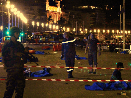Soldiers, police officers and firefighters walk near dead bodies covered with a blue sheets on the Promenade des Anglais seafront in the French Riviera town of Nice on July 15, 2016, after a truck drove into a crowd watching a fireworks display. At least 75 people were killed when a …
