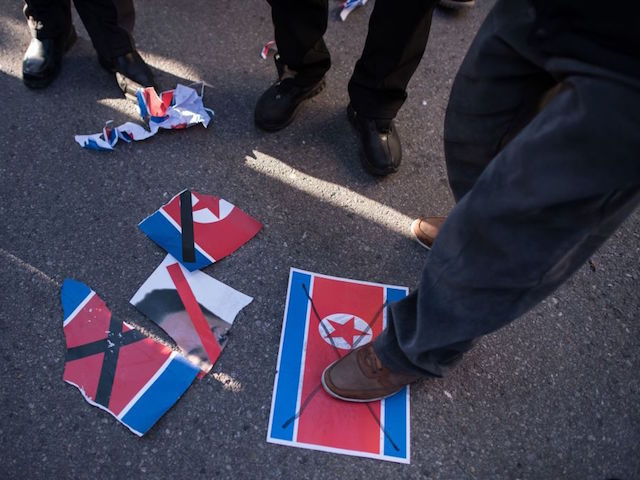 TOPSHOT - Anti-North Korean protesters step on a North Korean flag as a North Korean ferry