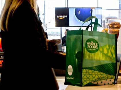 A customer stands at a coffee bar in front of an Amazon.com Inc. Pop-Up store inside the Lakeview Whole Foods Market Inc. store in Chicago, Illinois, U.S., on Monday, Nov. 20, 2017. Amazon.com Inc. is betting that people shopping for discounted organic Thanksgiving turkeys at Whole Foods this week may decide …