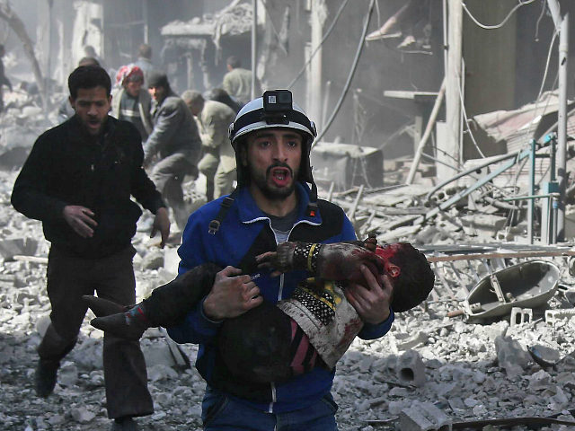 A Syrian civil defence member carries an injured child rescued from between the rubble of