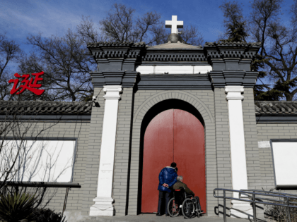 A man peeks through a main entrance gate of the Nantang Catholic Church in Beijing, Wednes