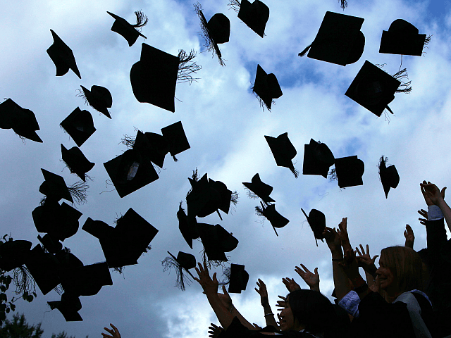 Students throw their mortarboards in the air during their graduation photograph at the Uni