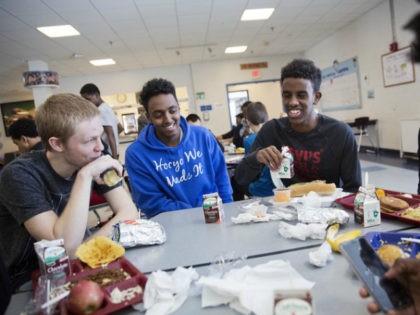 Abdiaziz Shaleh, right, a Lewiston high school senior and co-captain of the soccer team, and Essa Gedi, center, both whose families emigrated from Somalia, sit with classmate Isiah Leach, left, during lunch in the school's cafeteria in Lewiston, Maine, Wednesday, March 15, 2017. Two years ago, immigrant children led the …