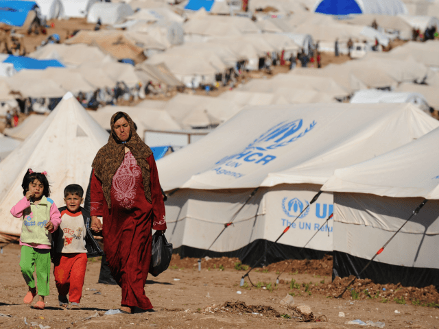 Syrian internally displaced people walk in the Atme camp, along the Turkish border in the
