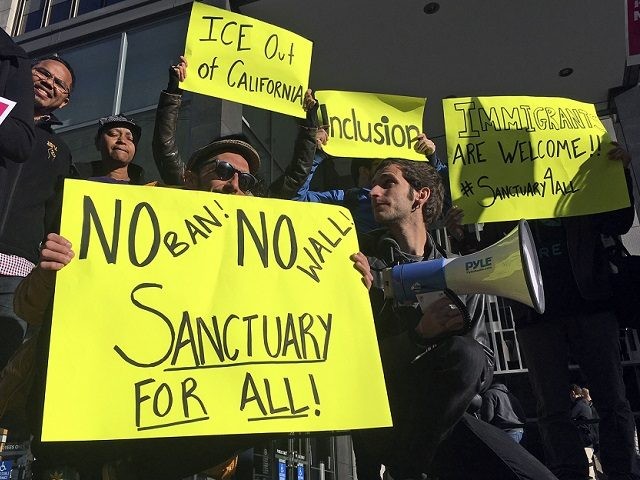 FILE - In this April 14, 2017, file photo, protesters hold up signs outside a courthouse where a federal judge was to hear arguments in the first lawsuit challenging President Donald Trump's executive order to withhold funding from communities that limit cooperation with immigration authorities in San Francisco. California state …