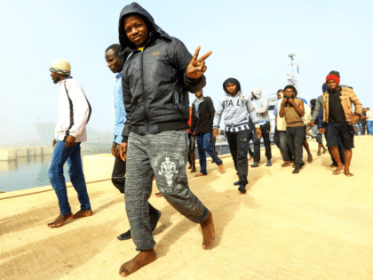 An African migrant flashes the victory gesture after disembarking following his rescue from off the coast of Zawiyah, about 45 kilometres west of the Libyan capital Tripoli, at the dock at the capital's naval base on March 10, 2018. / AFP PHOTO / MAHMUD TURKIA (Photo credit should read MAHMUD …
