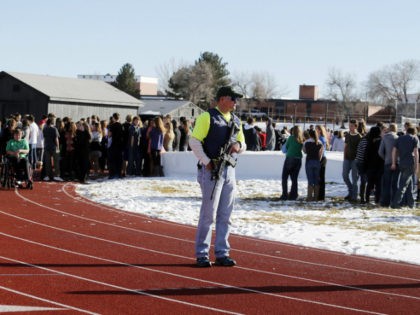 Sheriffs deputies stand guard over students after they were evacuated to the track and football field at Arapahoe High School in Centennial, Colo., on Friday, Dec. 13, 2013, where a student shot at least one other student at a Colorado high school Friday before he apparently killed himself, authorities said. …
