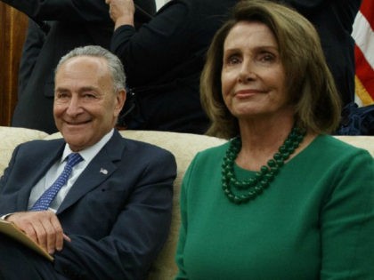 Chuck Schumer sits with Nancy Pelosi, both smiling.