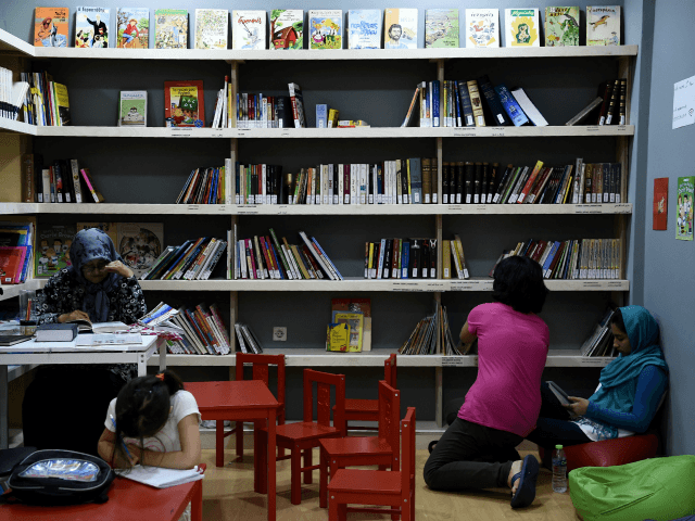 Refugees read books at a library set up on the premises of an international non-government