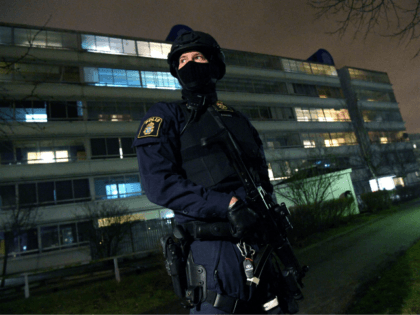 An armed police officer stands guard after an object exploded next to a police station in